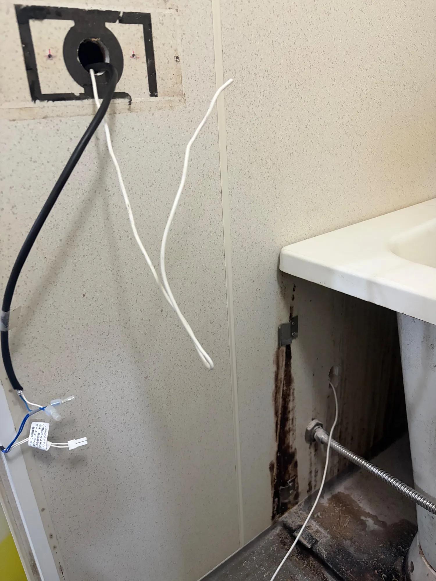 浴室リモコンの線を通すために開けた穴。穴とリモコンの位置が離れているため、硬いアース線を先に通してから線を呼び込みました。この通線だけで2人がかりで30分かかっています。