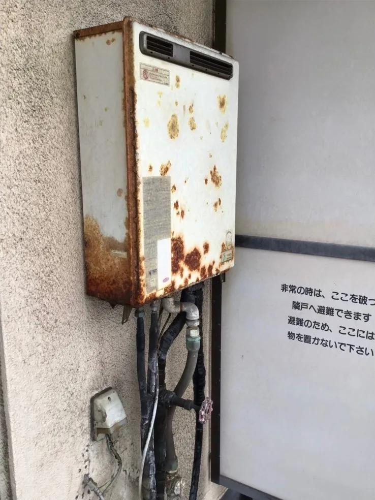 交換前の給湯器。屋外の壁に取り付けられ、下側から配管が伸びている