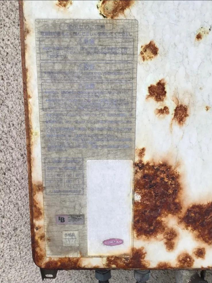 既設給湯器の正面。外装のあちこちが錆で膨らみ、注意書きのシールも色あせて型番の表示が読み取れない状態だった