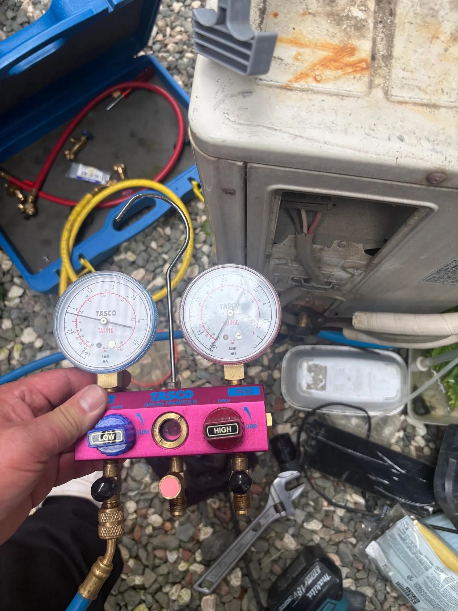 ゲージマニホールドで冷媒（R32）の圧力を確認。落下でフレア部が歪み、微量のガス漏れが起きていないかを停止時・運転時の圧力で点検した