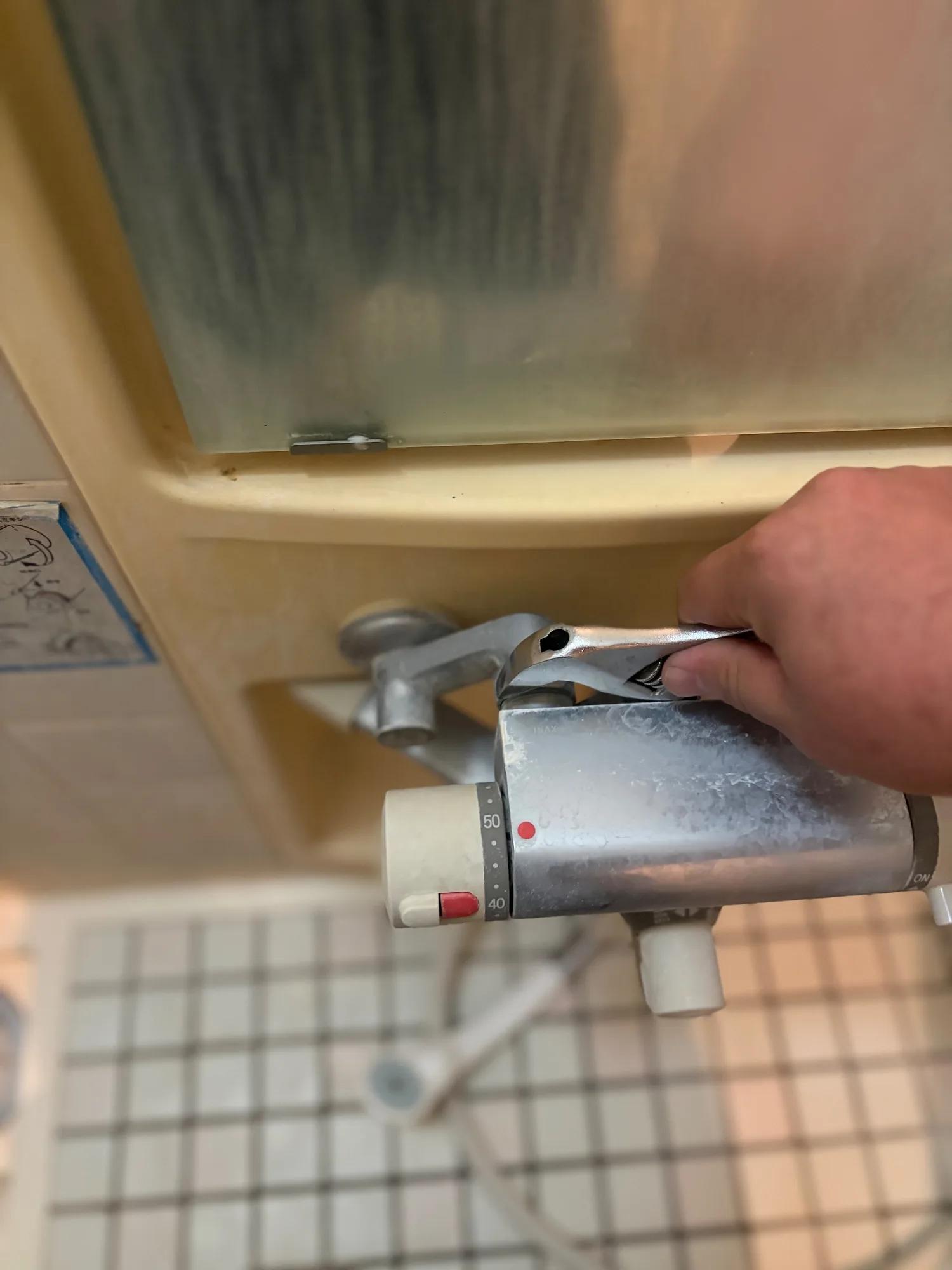 モンキーレンチで水栓本体のナットを緩め、既設の水栓を外しているところ