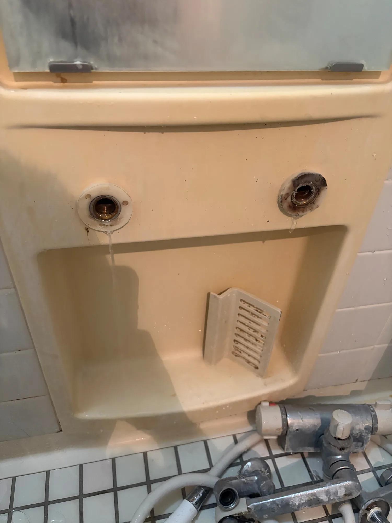 水栓を外した壁側。給水・給湯2か所のネジ穴だけが残り、向かって右側の穴まわりには赤茶色の汚れがたまっている