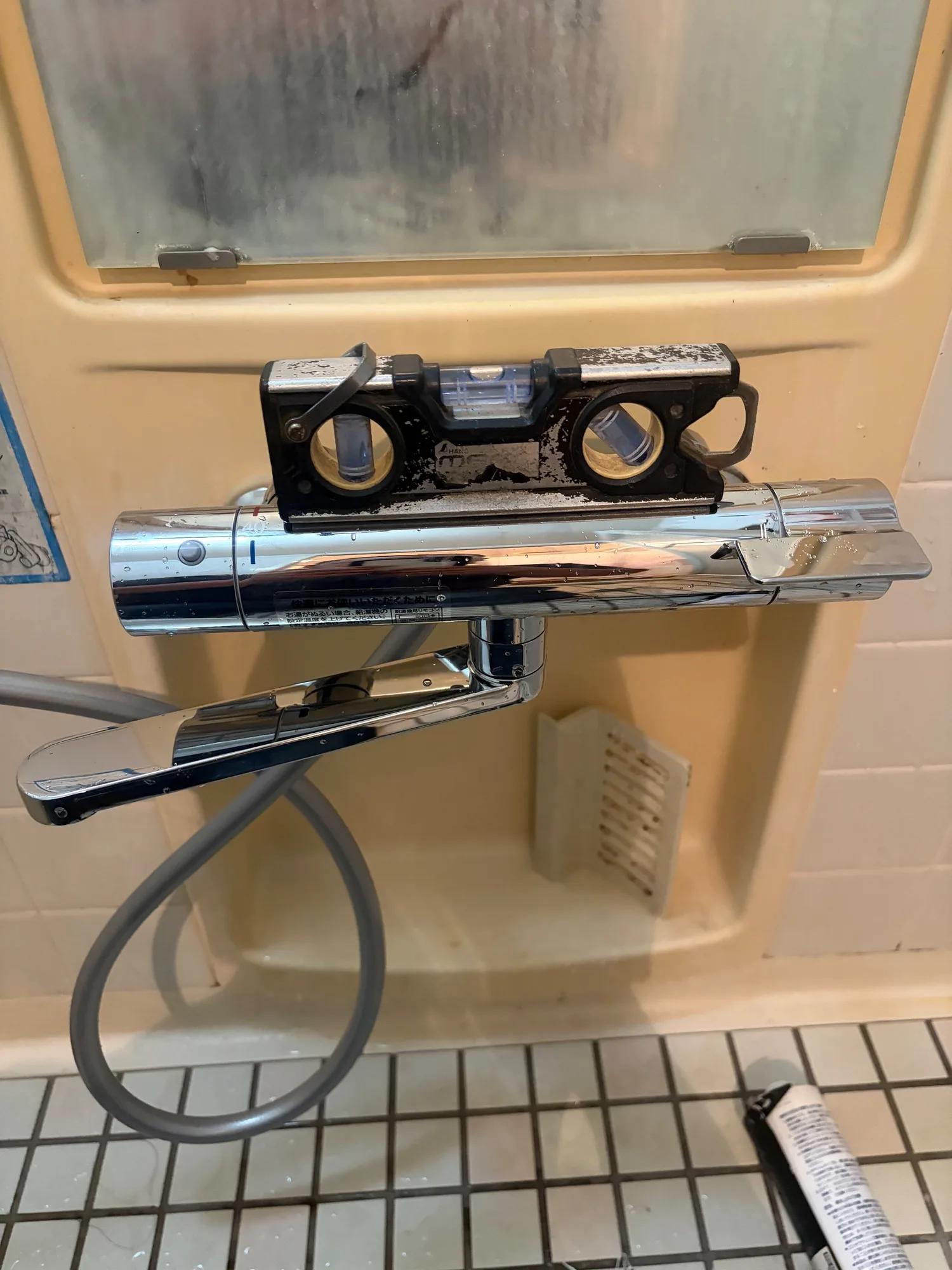 取り付けた新しい水栓本体に水平器を当て、傾いていないかを見ているところ