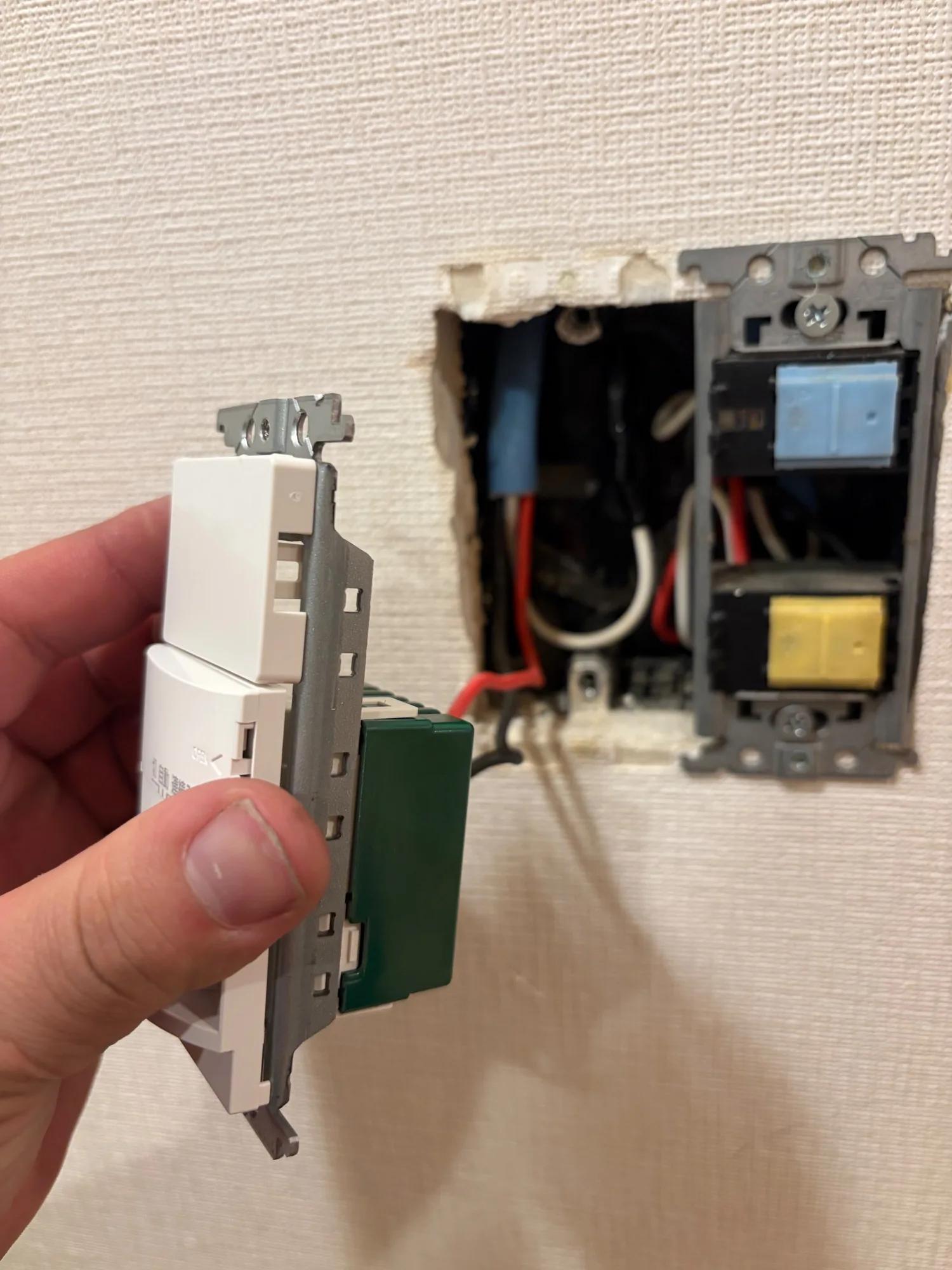 新しいスイッチを取付枠に組んだところ。壁の中には赤・黒の線が残っており、右側のコンセントはそのまま使っている
